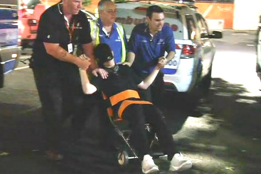 Three men assist a partygoer in a wheelchair outside Festival Hall.