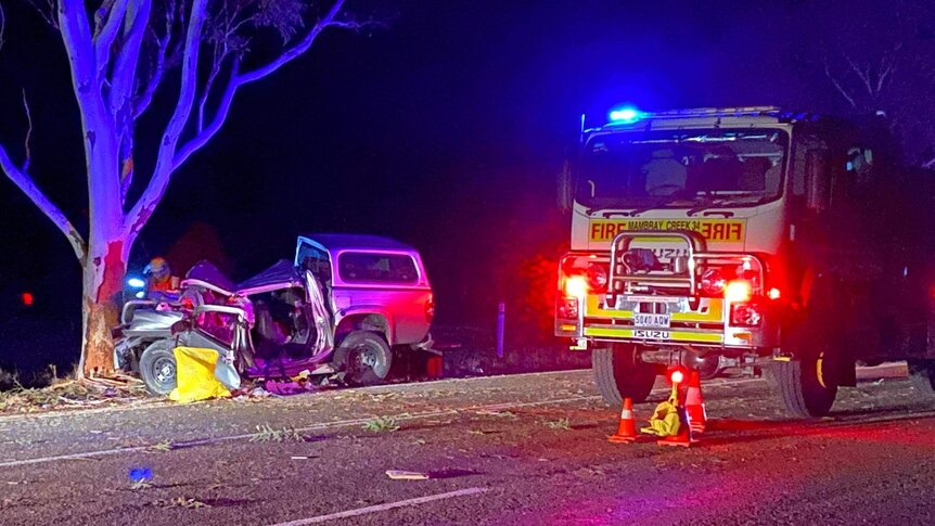 A fire truck next to a crashed ute at night on a road