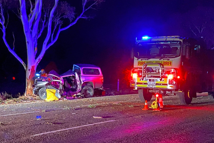 A fire truck next to a crashed ute at night on a road