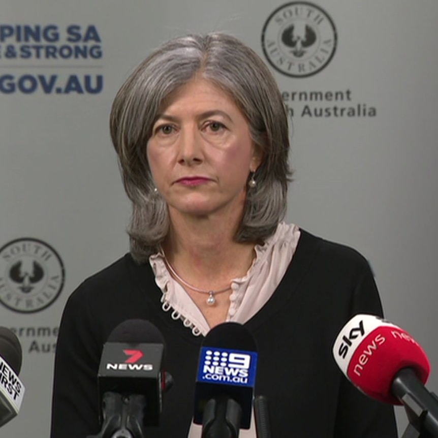 A woman with grey hair wearing a black cardigan and light pink top