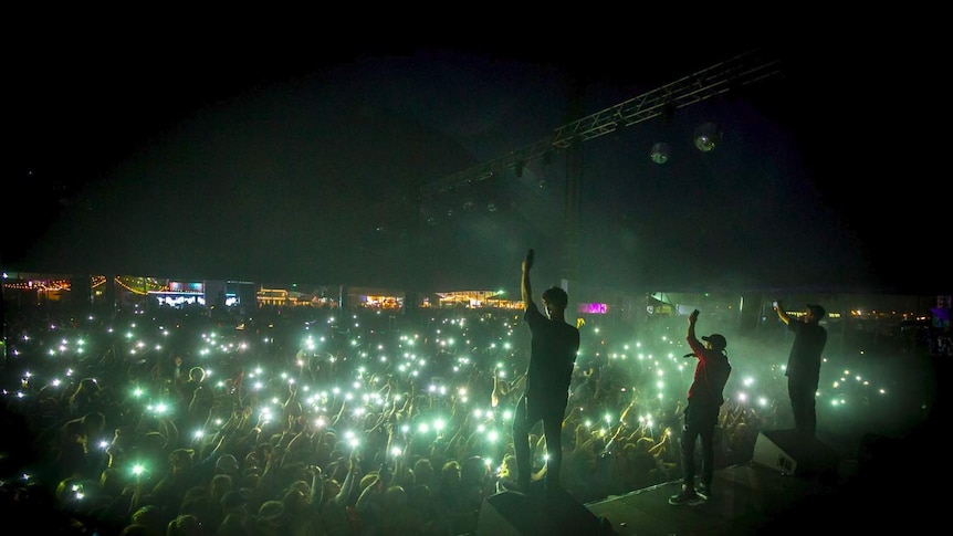Thundamentals raise their hands to a crowd illuminated by their mobile phones