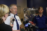 A man standing behind microphones