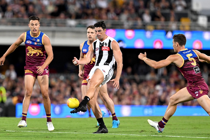 Scott Pendlebury kicks the ball as Lions opponents watch on