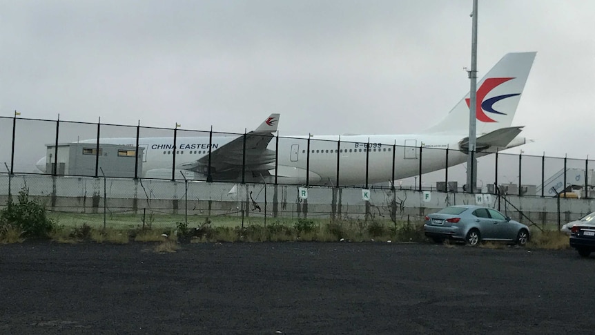 A China Eastern plane sitting on the tarmac at Sydney Airport after turning back because of a large hole in an engine.