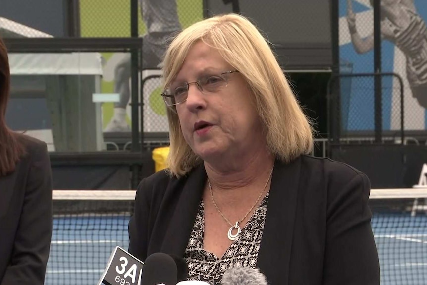 Lisa Nevill talking to media on a tennis court.