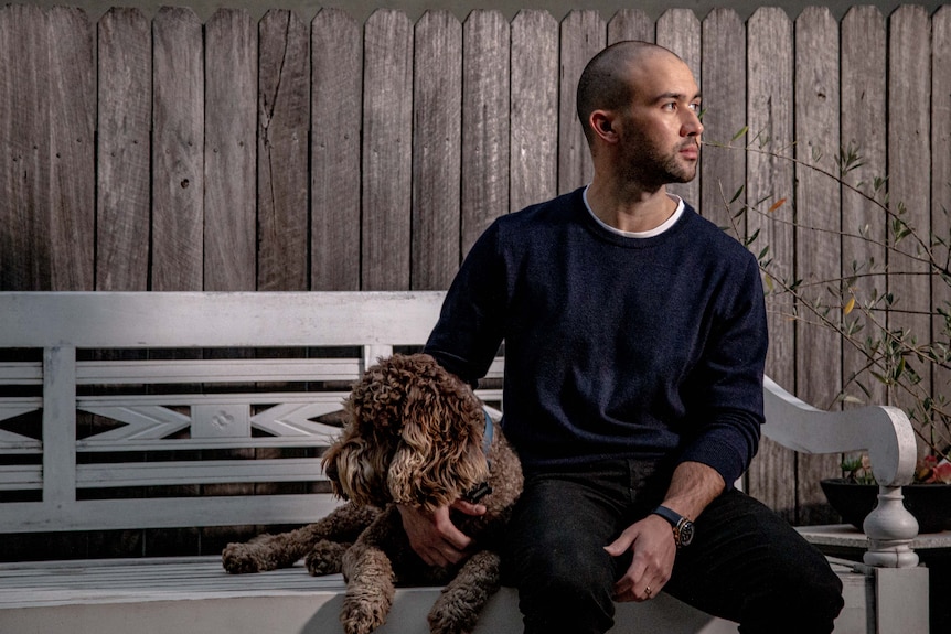 a man holding his dog on a bench