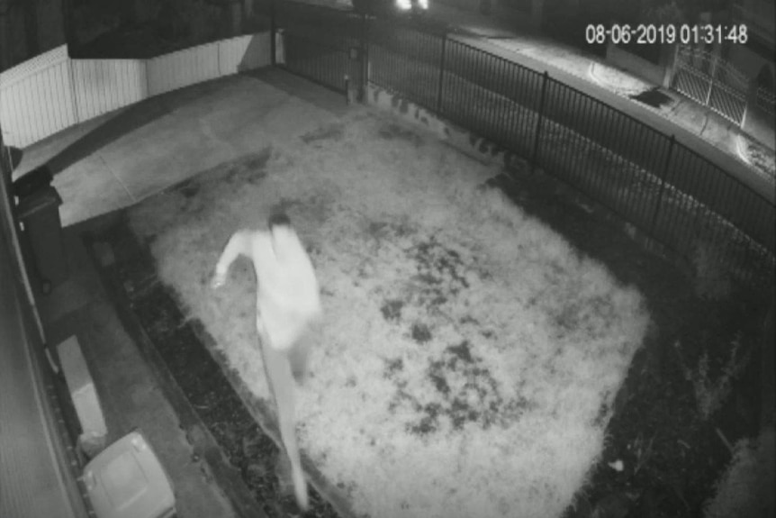 Black and white security camera footage shows a man running on the front lawn of a house