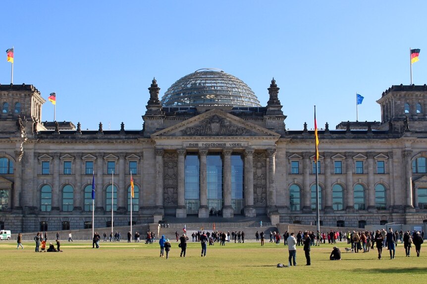 Blue skies backdrop to Berlin's Reichstag building with German flags lining the roof.