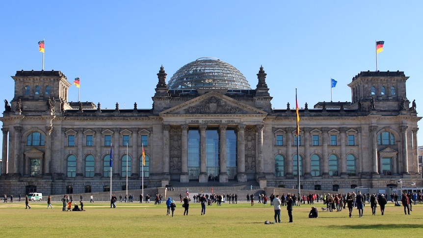 Blue skies backdrop to Berlin's Reichstag building with German flags lining the roof.