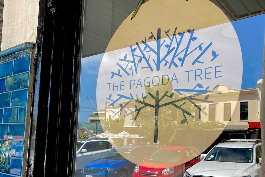 A yellow sign for The Pagoda Tree behind a window.