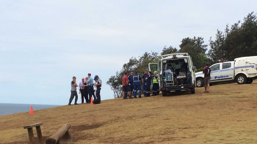 NSW ambulance workers and police talk on a hill near the sea