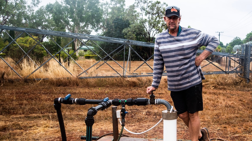 A man leans against a bore on his property