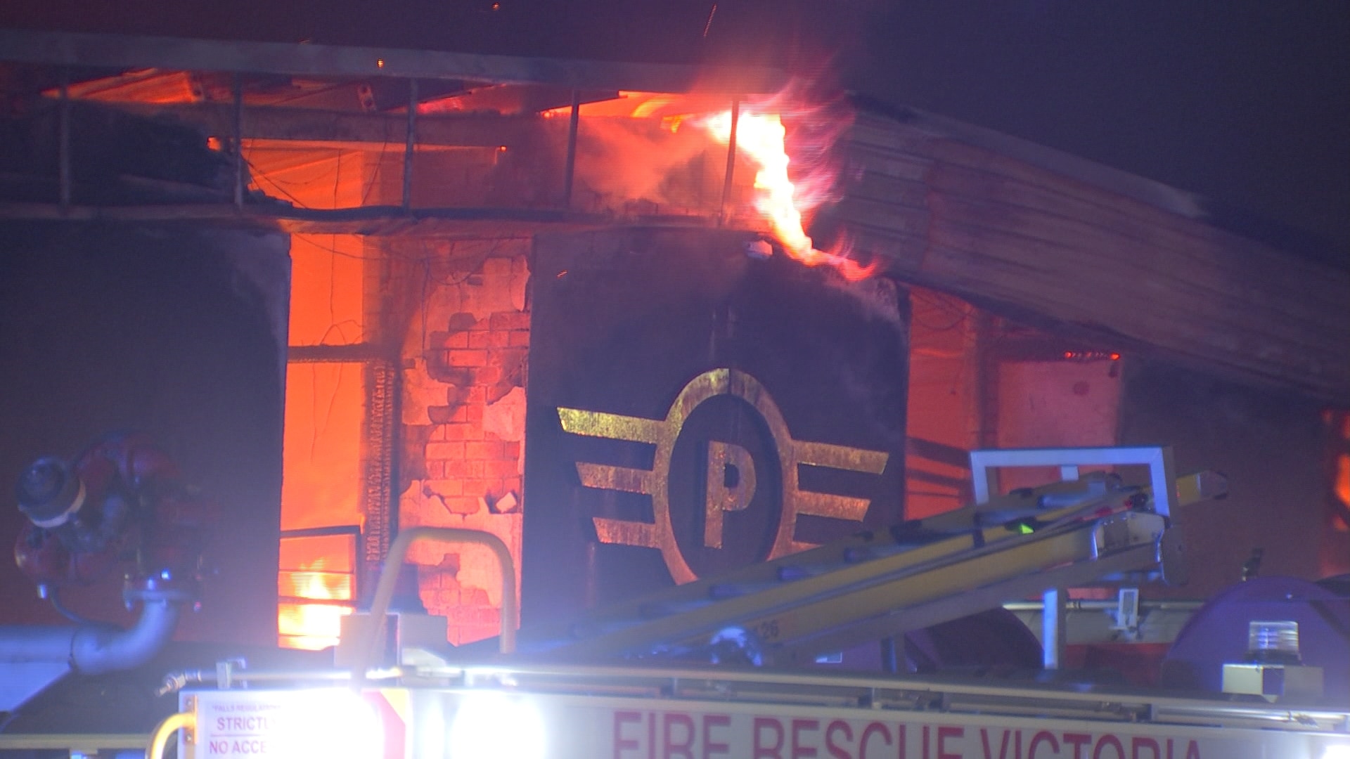 Orange flames can be seen inside a dark coloured building with a logo featuring the letter P on the exterior.
