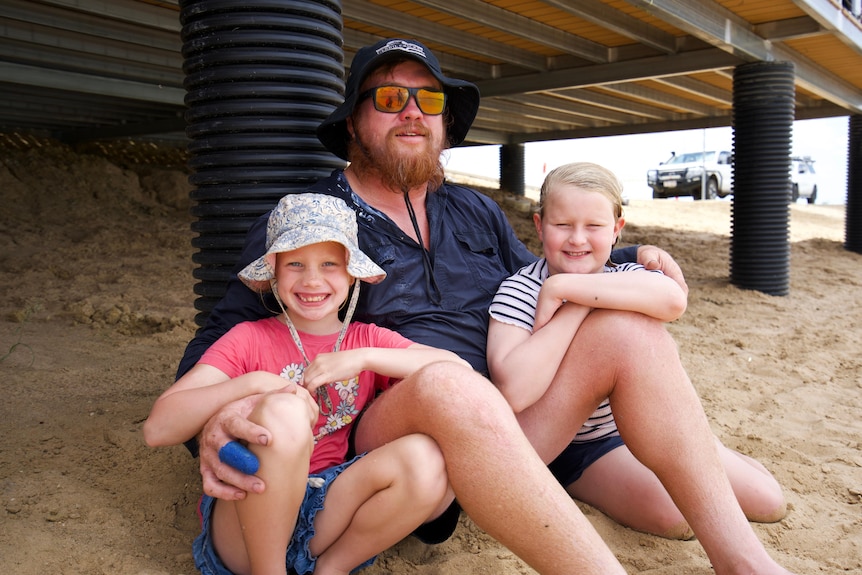Man on beach with two daughters