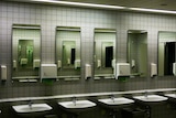 Row of sinks in public bathroom with soap and paper towel dispensers