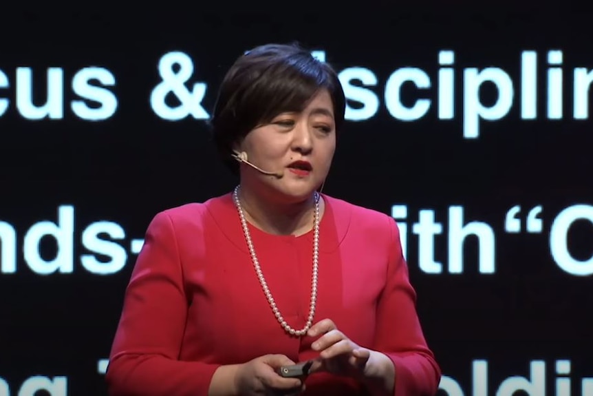 A woman in a red top and pearls 