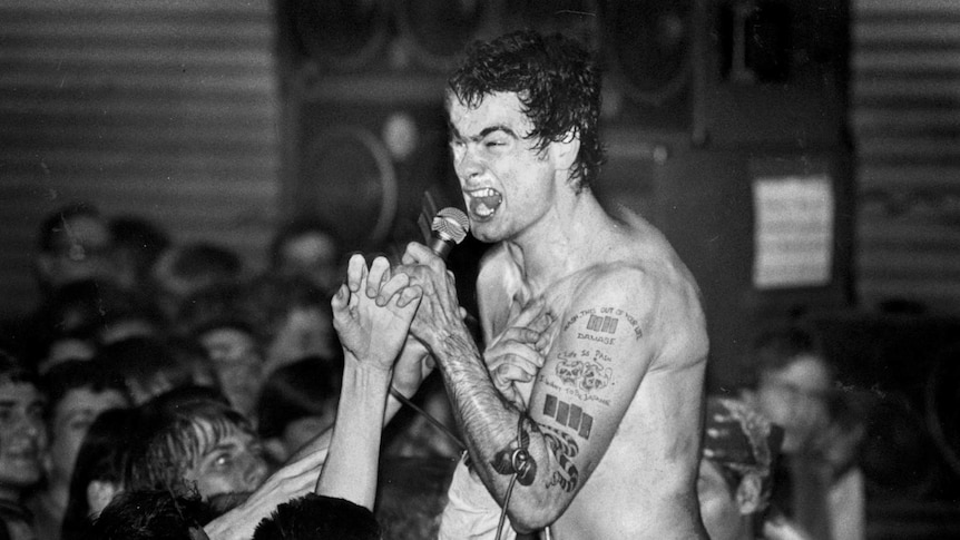 Black and white image of henry Rollins singing in a crowd after stage diving,  an intense look on his face