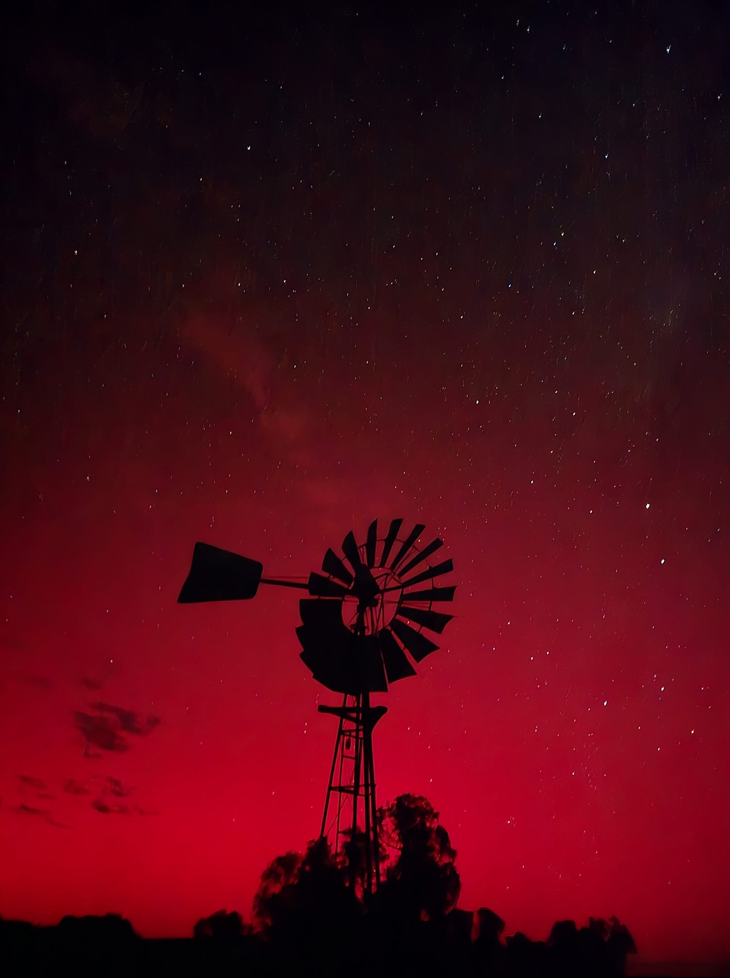 A red sky above a silhouetted windmill.