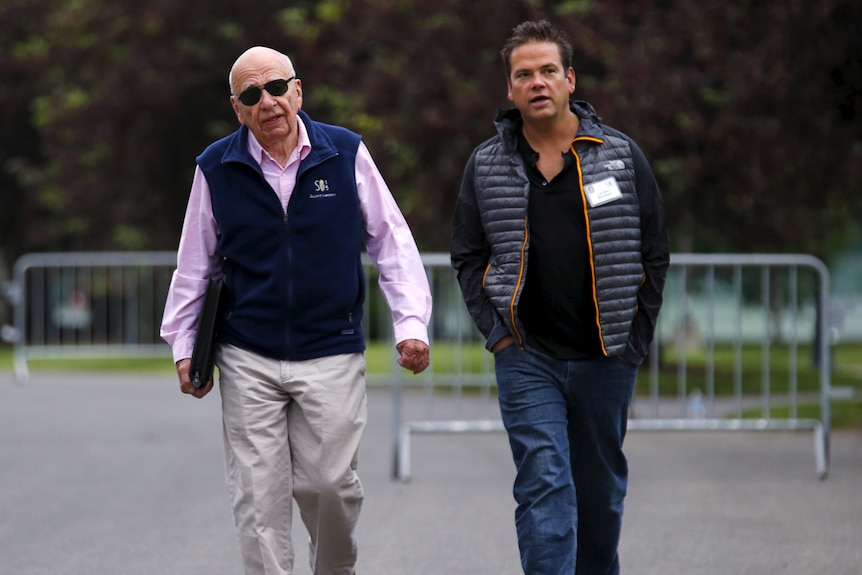 rupert and lachlan in shirts and vests, rupert in sun glasses carrying a briefcase under his arm