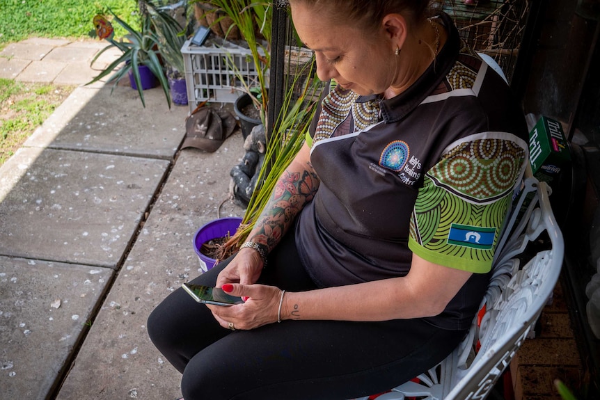 Helen Eason holds a mobile phone and types on it.