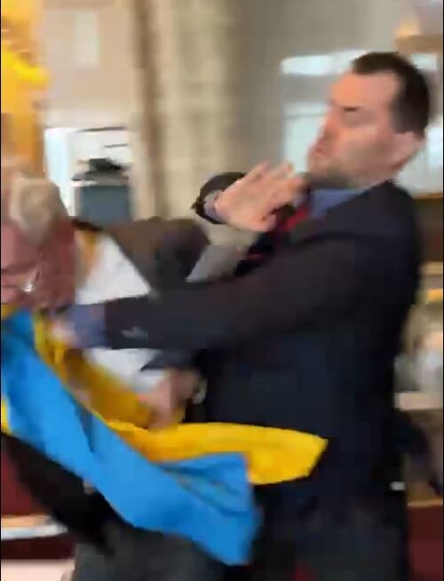 A man in a suit punches an older man in a suit.