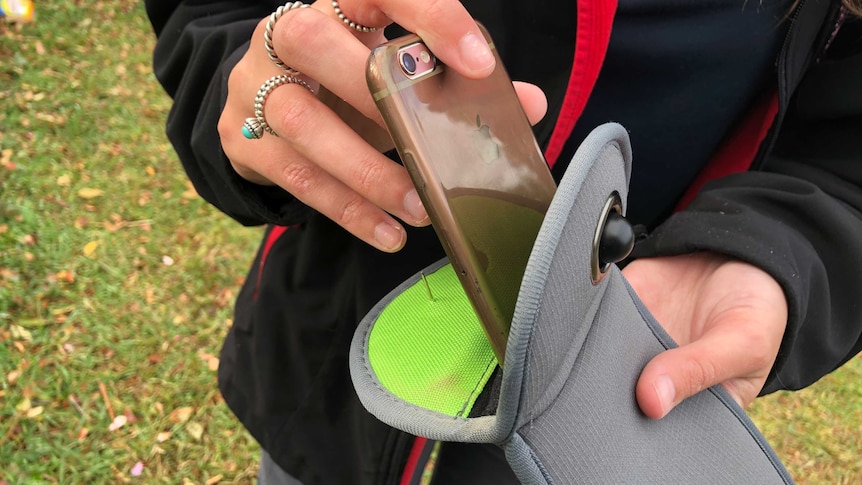 A student puts a phone in a Yondr lock case