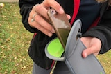A student puts a phone in a Yondr lock case