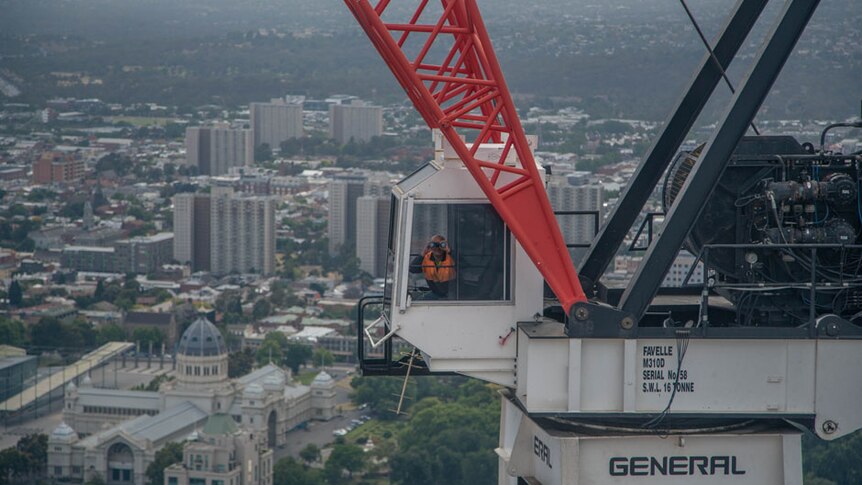 Crane operator Ray peers through his binoculars from inside the crane cabin