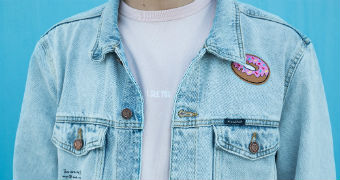 Close up of man wearing shirt and denim jacket standing by a blue wall