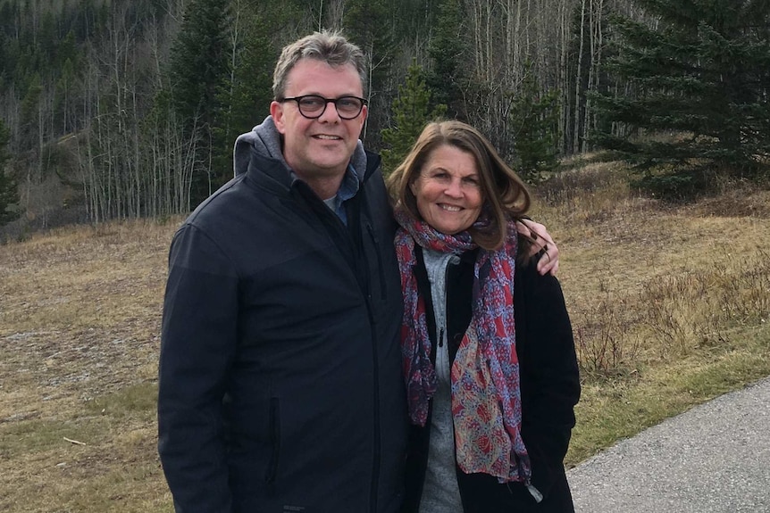 Kevin Garratt and his wife Julia stand in front of mountains.