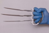 A gloved hand holds bladed knuckledusters.
