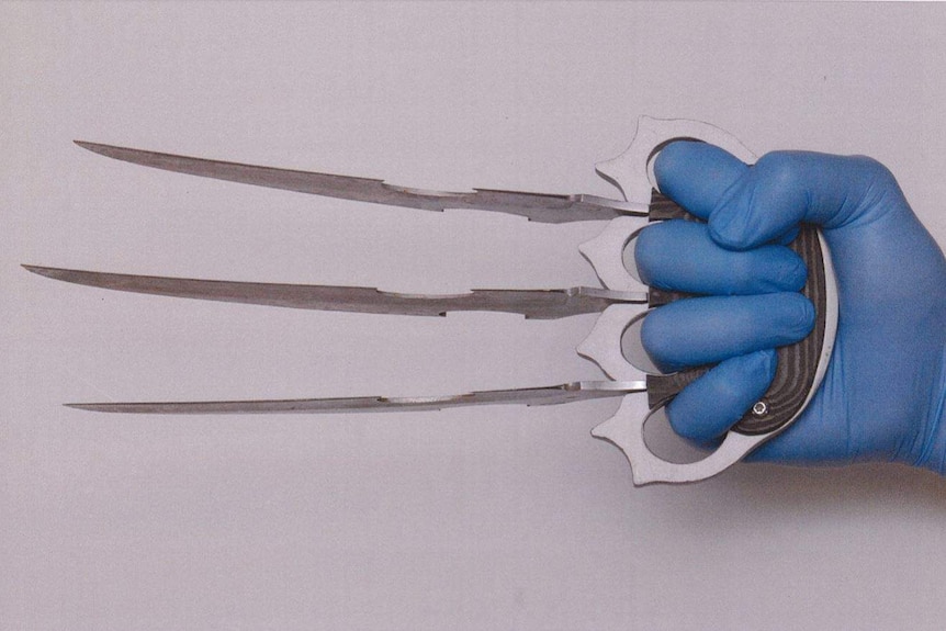 A gloved hand holds bladed knuckledusters.