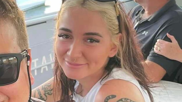 A smiling young woman with sunglasses on her head.