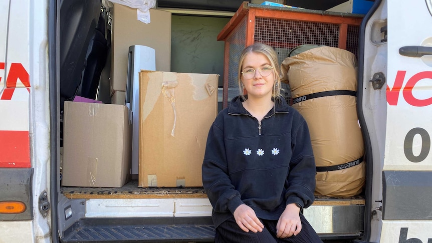 A young woman in a van with moving boxes