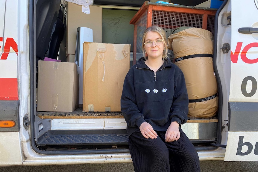 A young woman in a van with moving boxes