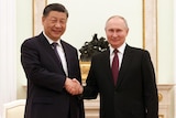 Chinese President Xi Jinping and Russian President Vladimir Putin shake hands as they pose for a photo.