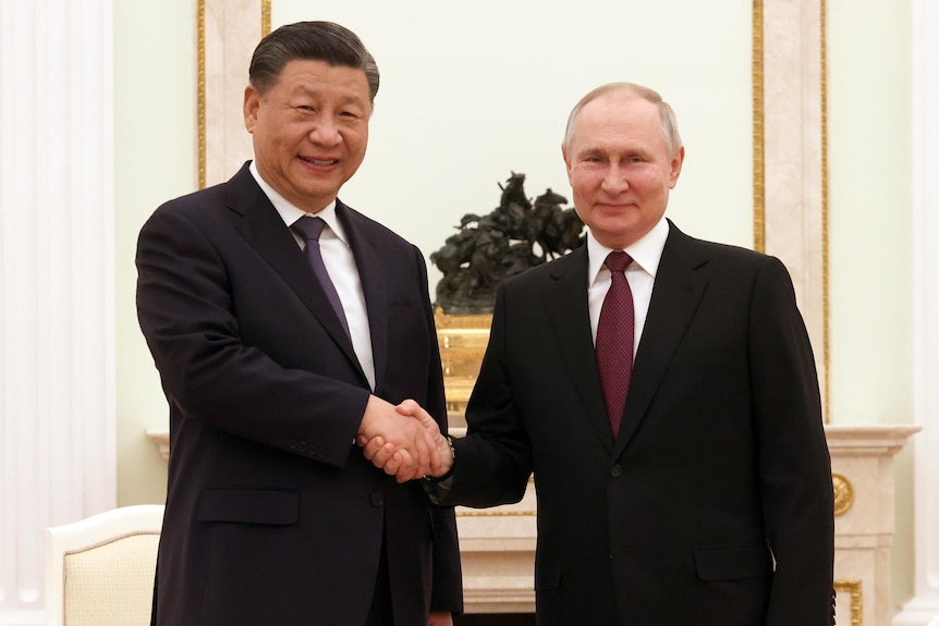 Chinese President Xi Jinping and Russian President Vladimir Putin shake hands as they pose for a photo.