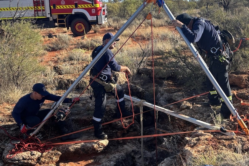 A fire engine and emergency services personnel work to free a woman from a cave.