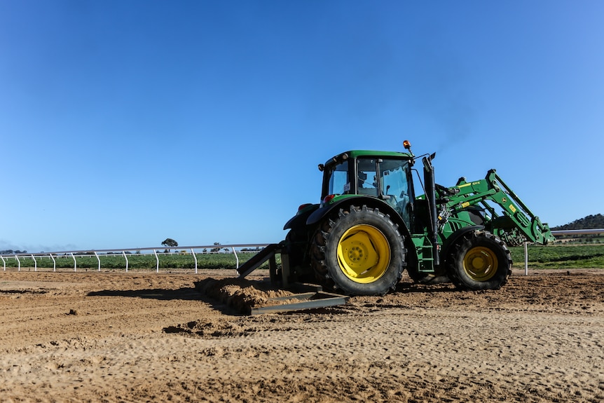 A tractor smoothing out the sand training track.