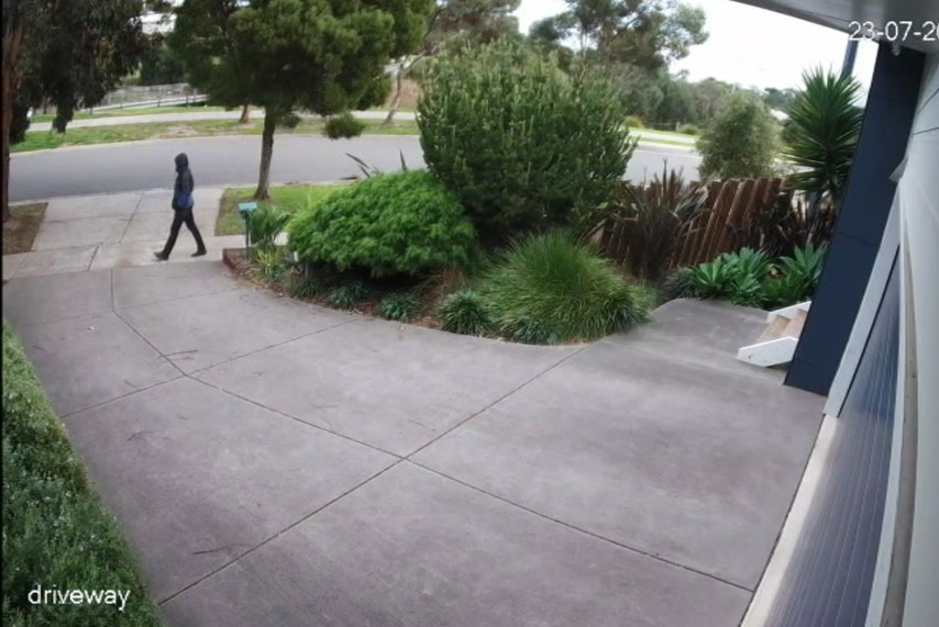 A man dressed in dark clothing including a hoodie walks past the end of a driveway at Samantha Fraser's house.