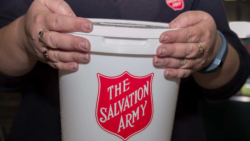Close up of a woman's hands holding a white bucket with The Salvation Army written in red on it.