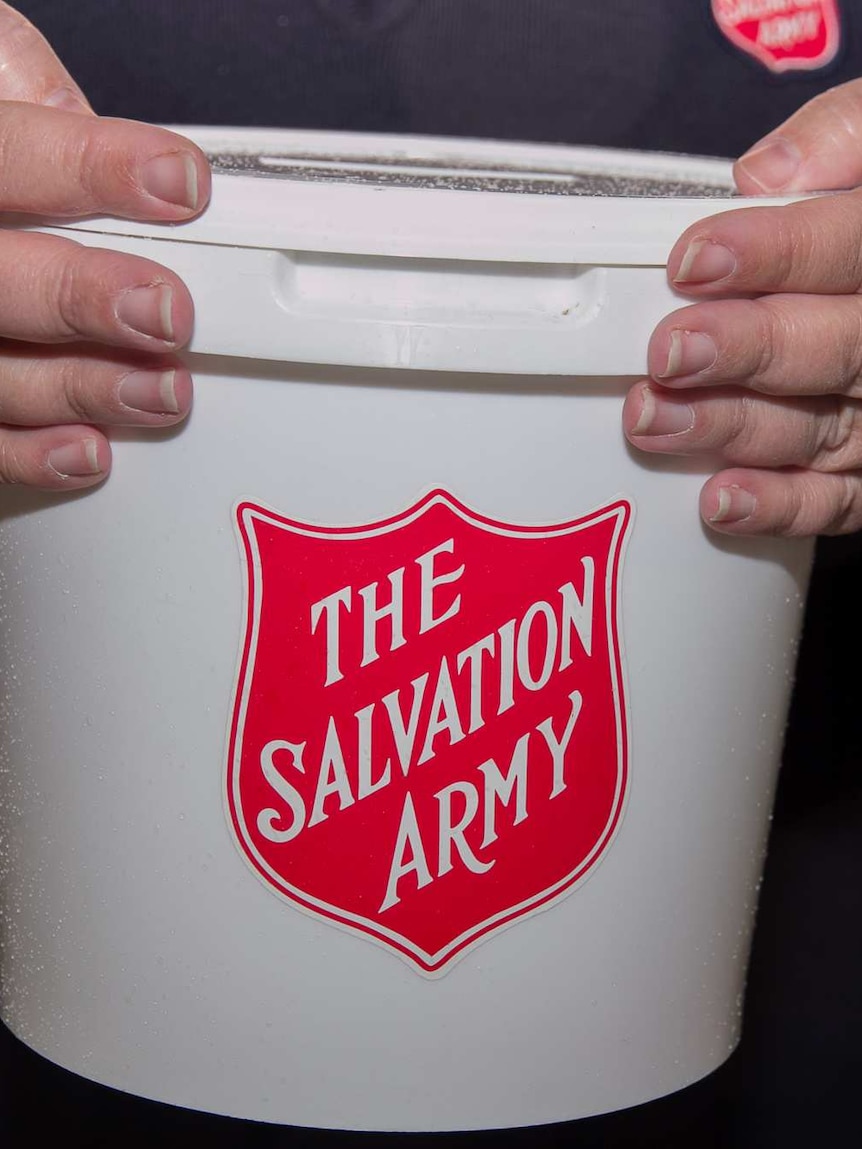 Close up of a woman's hands holding a white bucket with The Salvation Army written in red on it
