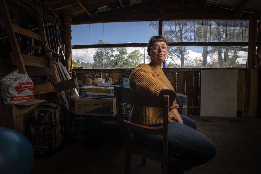 A woman sitting on a chair in a suburban shed