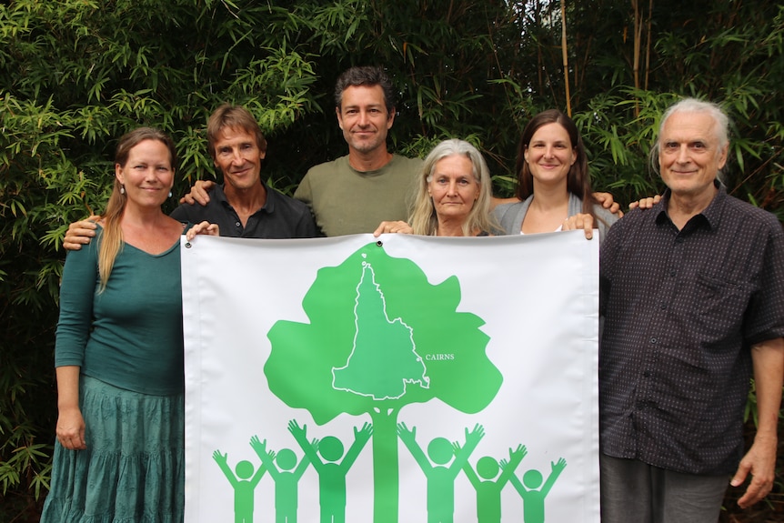 Six volunteers standing behind the Spray Free FNQ Flag