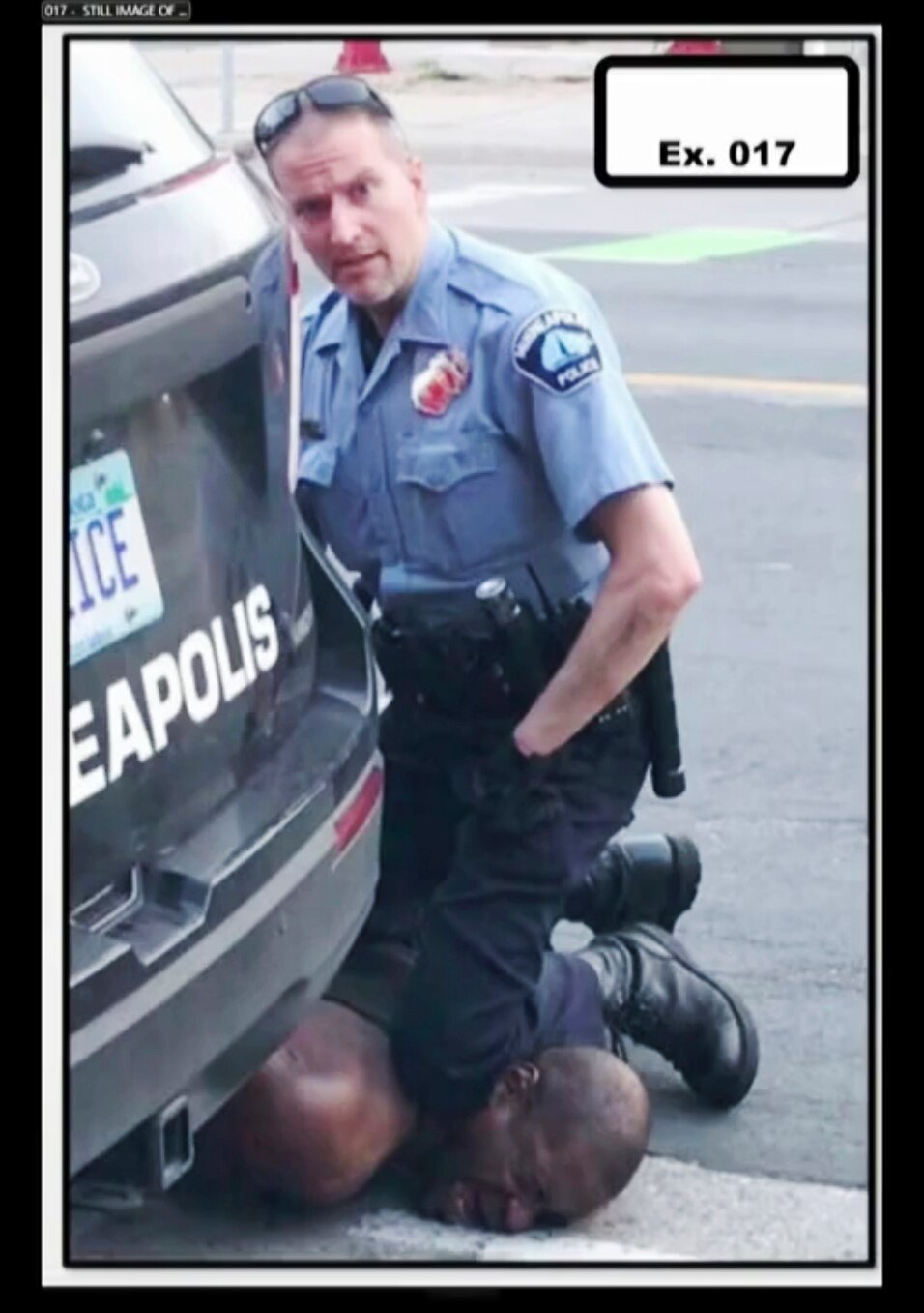 A police officer kneels on the neck of George Floyd.