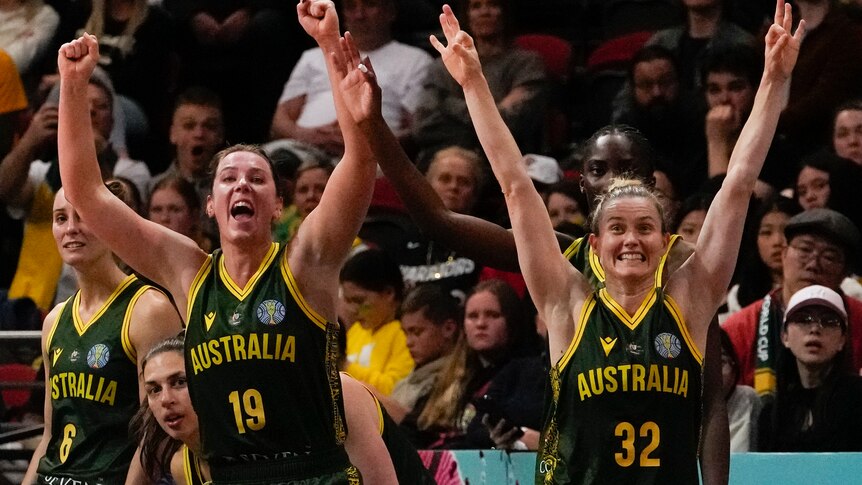 Two Australian women's basketball team players raise their arms in celebration.