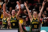 Two Australian women's basketball team players raise their arms in celebration.