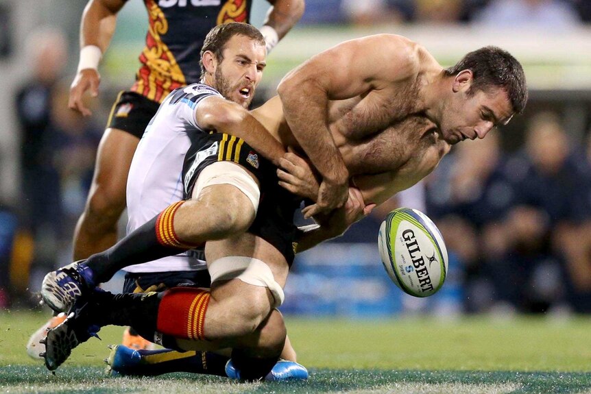Brumbies player Nic White tackles a shirtless Nick Crosswell, of the Chiefs, during the Brumbies victory.
