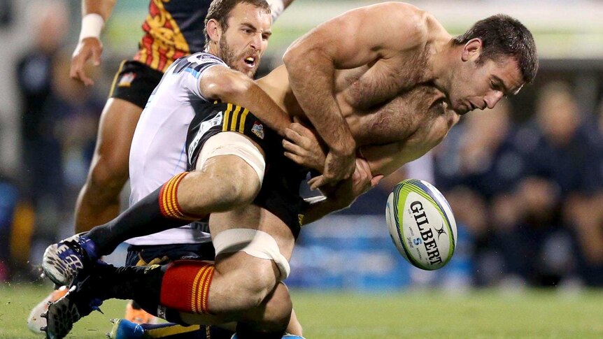 Brumbies player Nic White tackles a shirtless Nick Crosswell, of the Chiefs, during the Brumbies victory.