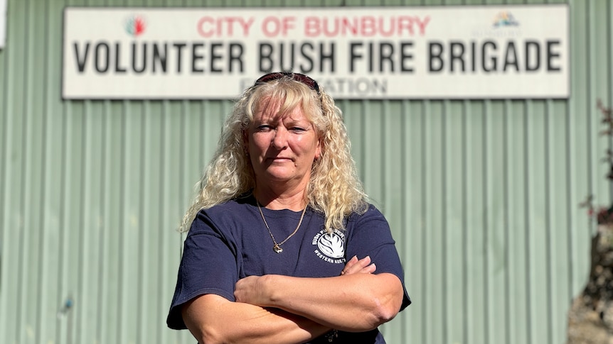 A blonde women stands with crossed arms in from of Bunbury Volunteer Bush Fire Brigade station.